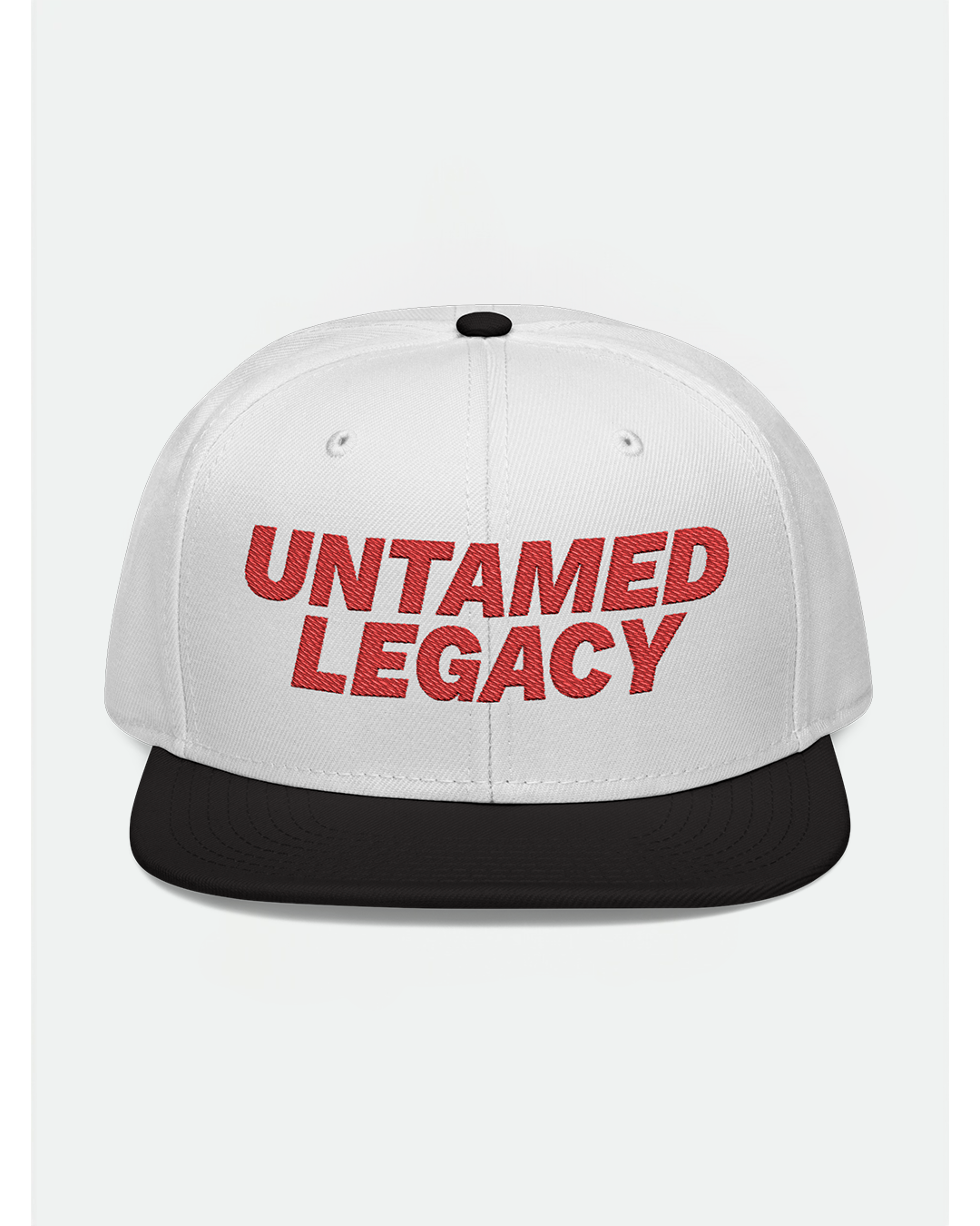 White snapback hat with contrasting black brim and bold red embroidered “Untamed Legacy” logo — a timeless urban essential.